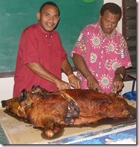 Clovis and Roy carving the roast pig